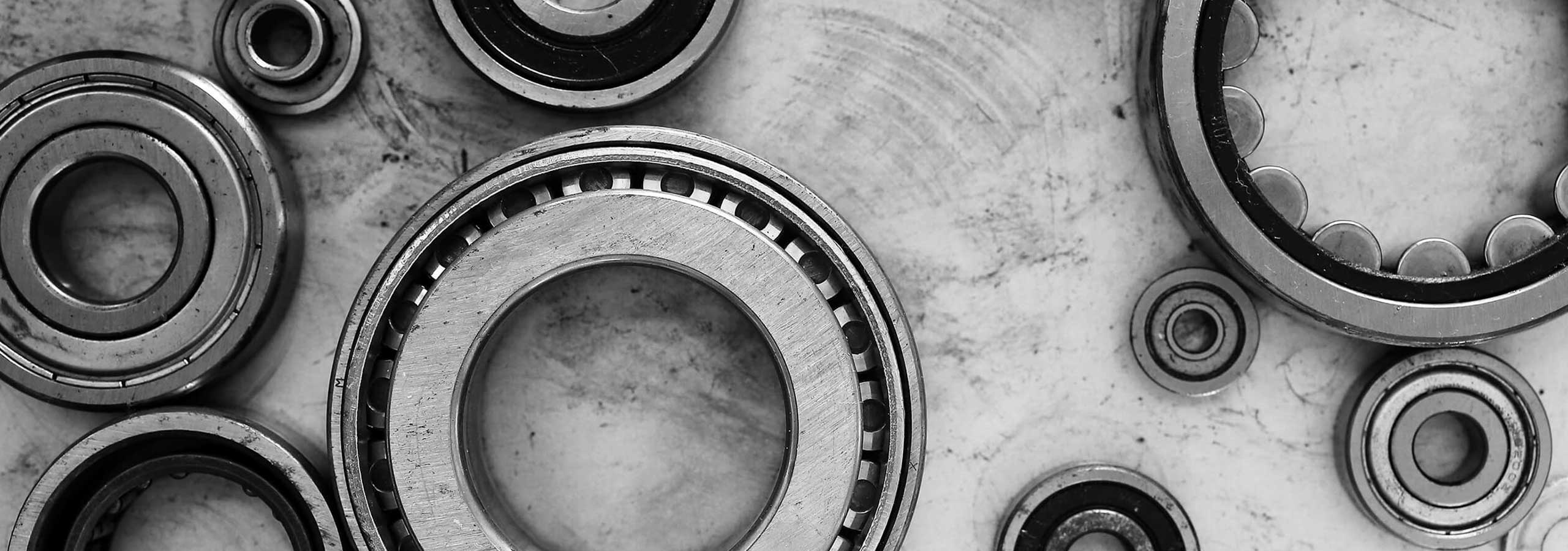 A monochrome close-up arrangement of industrial ball bearings and roller bearings