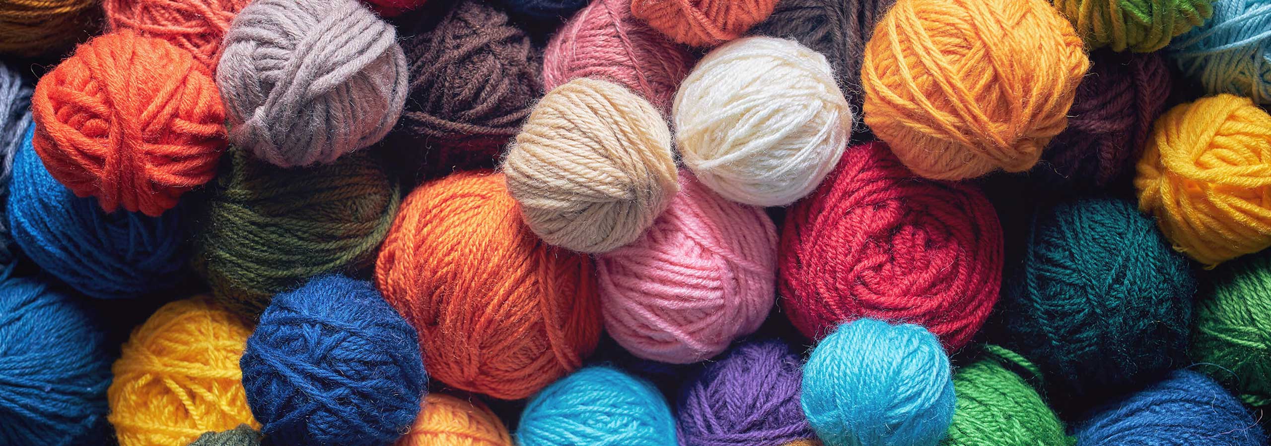 A close-up, top-down view of multiple colorful balls of yarn tightly packed together